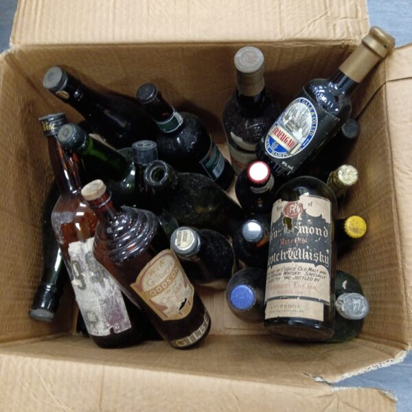 Assorted vintage beer and wine bottles in a cardboard box.