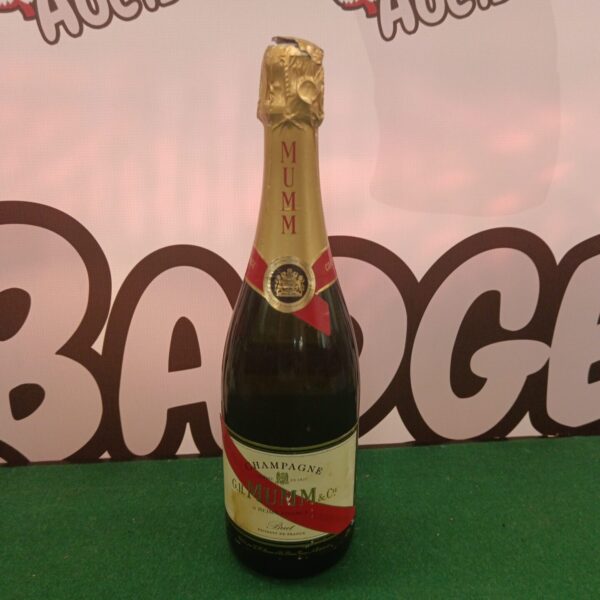 G h Mumm Cordon Rouge Champagne bottle on a green background.