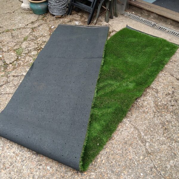 Roll of green astro turf in a garden setting.