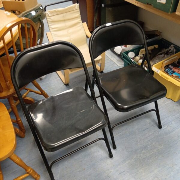 Two black metal folding chairs shown indoors.