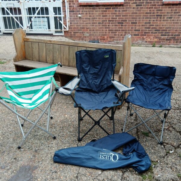 Three folding camping chairs in a garden setting.