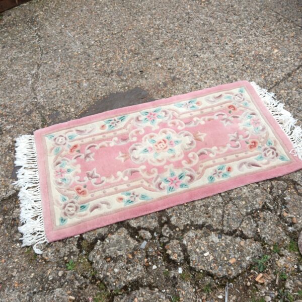 Vintage pink floral rug with a woven texture.