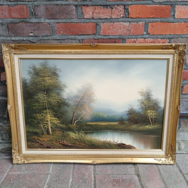 Vintage gilt framed oil painting of a tranquil lake landscape.