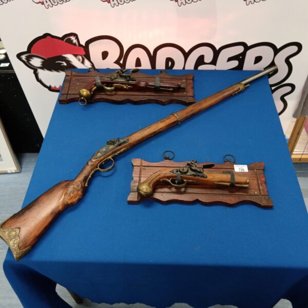 Antique flintlock pistol and rifle wall display for collectors.