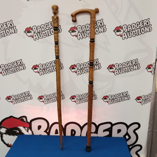 Two intricately carved African walking sticks displayed indoors.