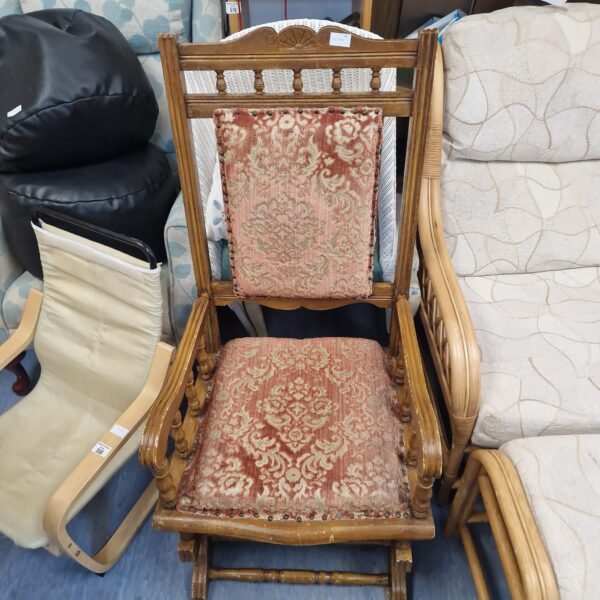 Antique rocking chair with patterned upholstery and carved wood.