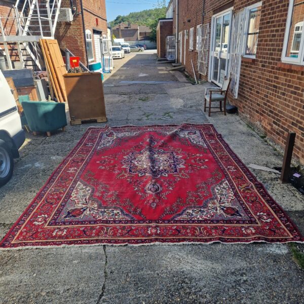 Large red floral rug in a courtyard setting.