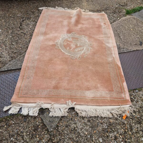 Pink rug with oriental dragon pattern, approximately 6x4 feet.