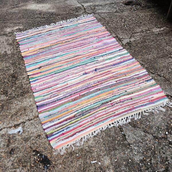 Colourful rag rug with a braided texture on a concrete floor.