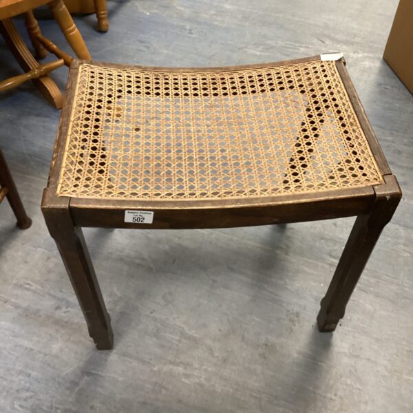 Vintage rattan stool with woven seat and wooden legs.