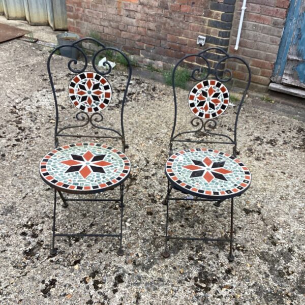Vintage wrought iron garden chairs with colourful tile tops.
