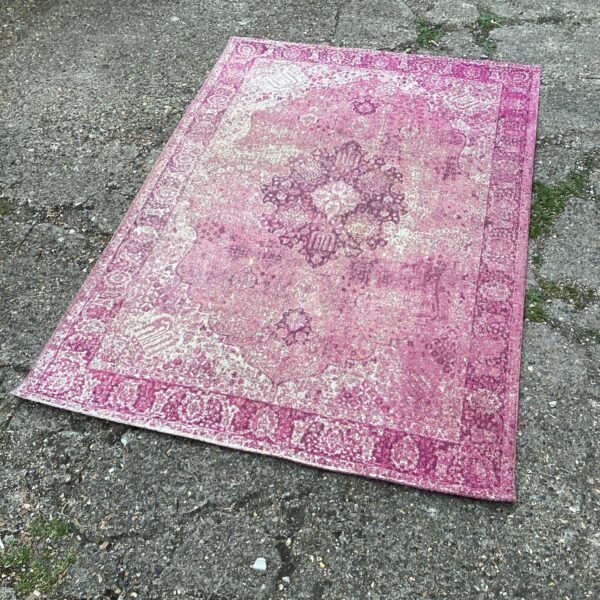 Vintage pink area rug with floral pattern for home decor.