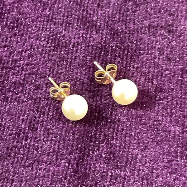 Close-up of 9ct gold pearl stud earrings, elegant jewellery.