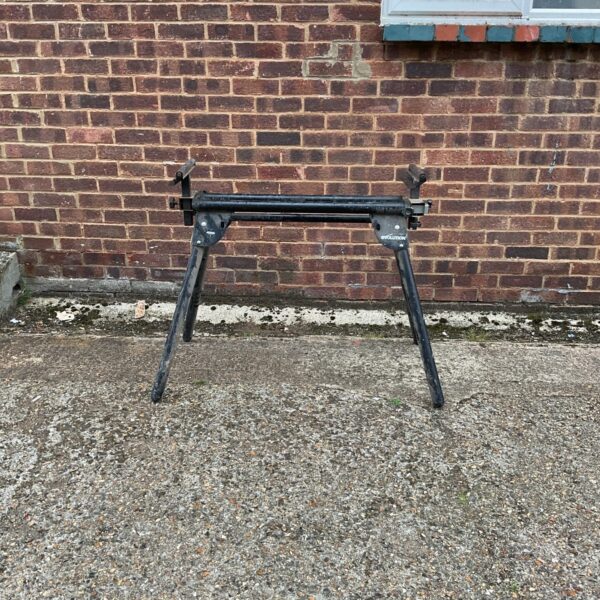 Adjustable metal work table with rollers for workshop use.