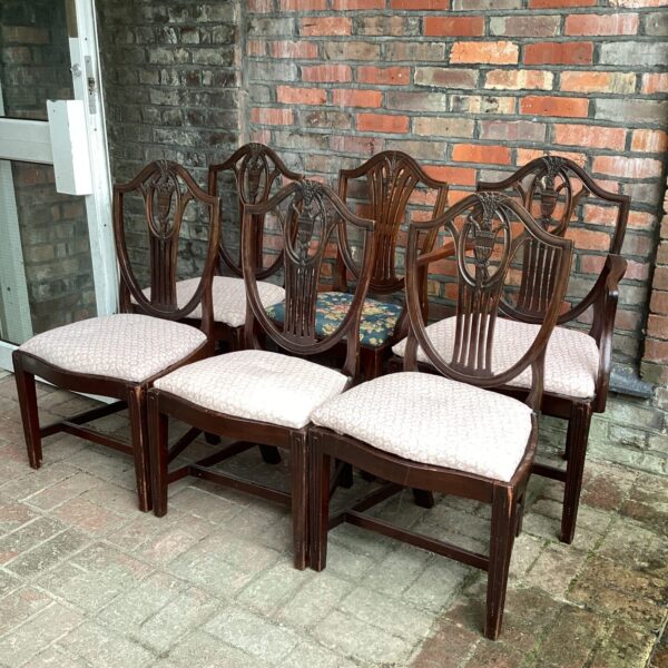 Six antique dining room chairs with upholstered seats.
