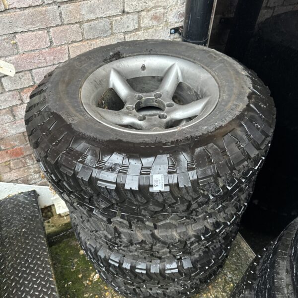 Stack of L200 alloy wheels with off-road tyres.