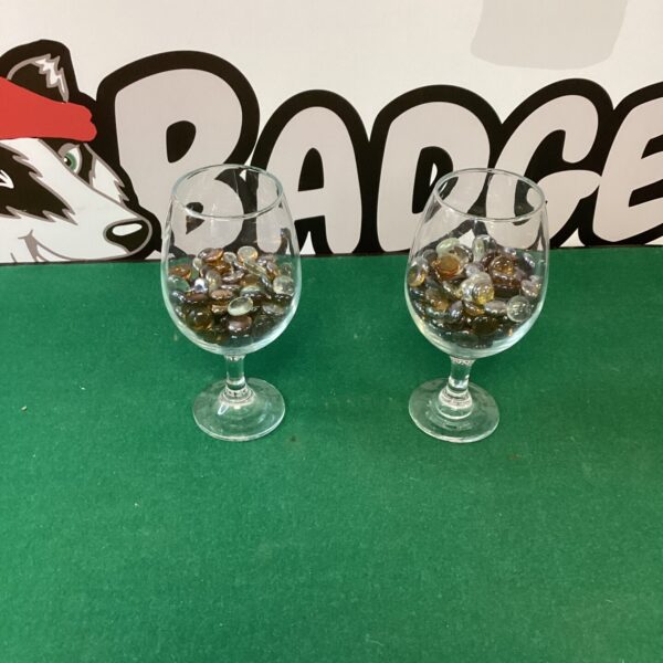 Two large wine glasses filled with colourful glass beads for display.