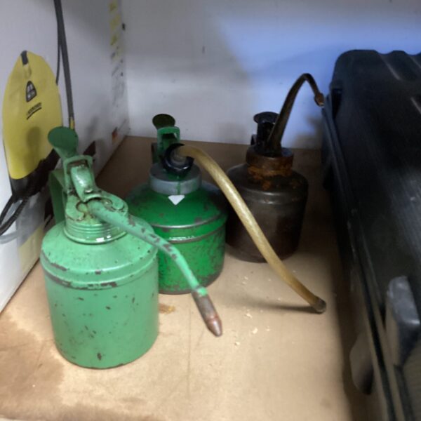 A collection of three vintage metal oil cans with spouts.