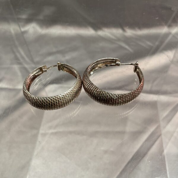 Large silver hoop earrings with a textured rope design.