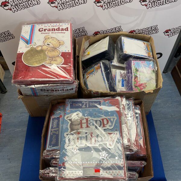 Mixed lot of birthday cards and celebration items in cardboard boxes.
