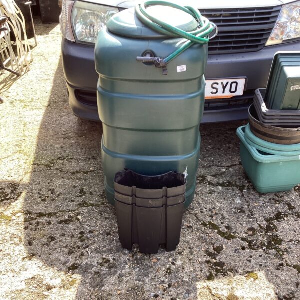 Green garden water butt with stand in an outdoor setting.