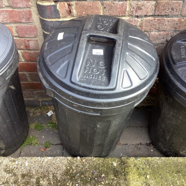 Black plastic garden dustbin for outdoor waste storage.