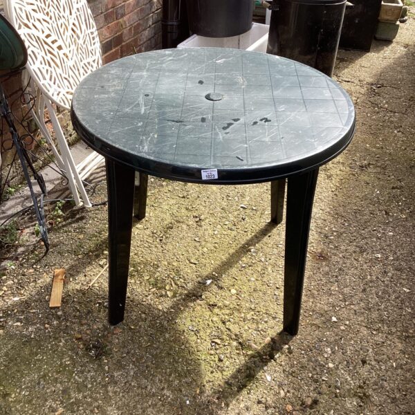 Round plastic garden table in an outdoor setting.