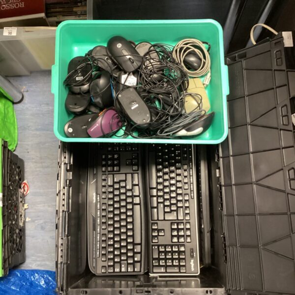 A crate filled with various Logitech keyboards and computer mice.