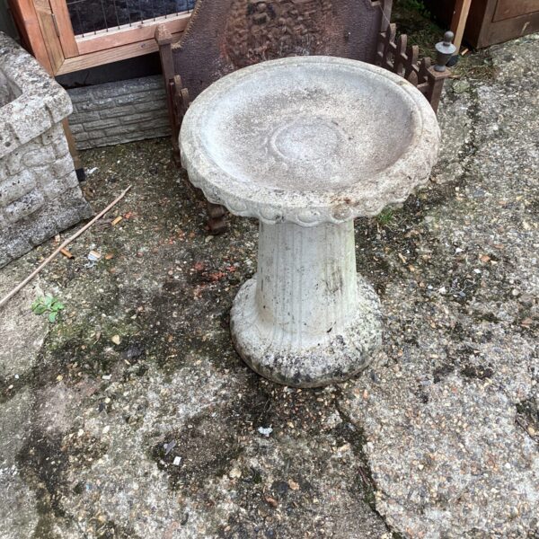Classic stone effect bird bath in a garden setting.