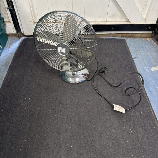 Silver vintage M&S metal desk fan on a dark surface.