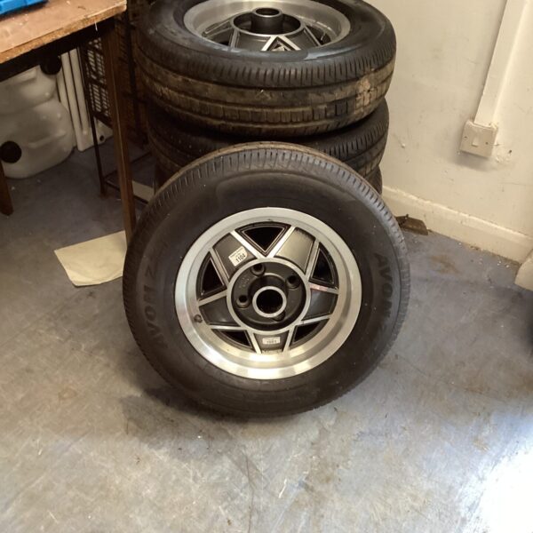 Stack of five alloy car wheels with new tyres.