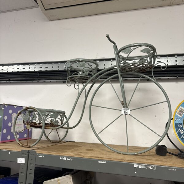 Vintage metal tricycle plant stand with a basket for plants.