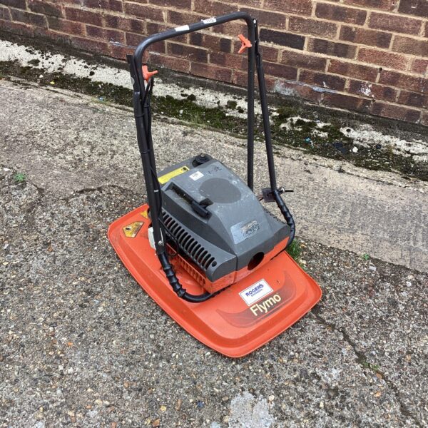 Side view of a used Flymo petrol lawn mower.