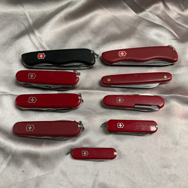 Lot of nine Victorinox Swiss Army knives, red handles, multi-tool.