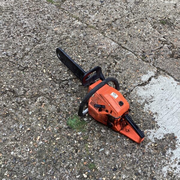Orange vintage petrol chainsaw, a classic garden tool.