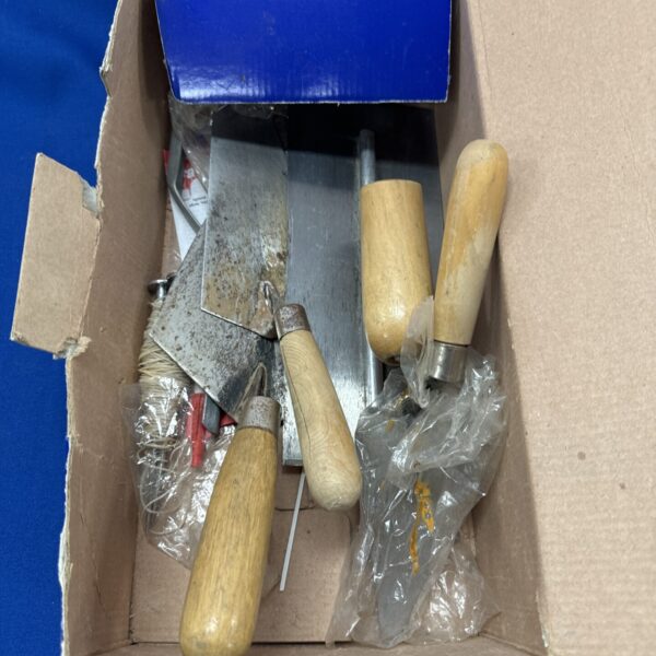 Selection of used trowels and floats with wooden handles.