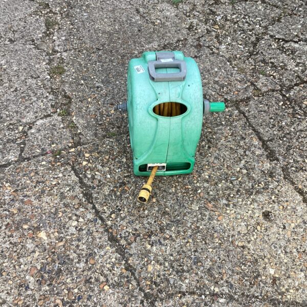 Green plastic garden hose reel for outdoor watering.