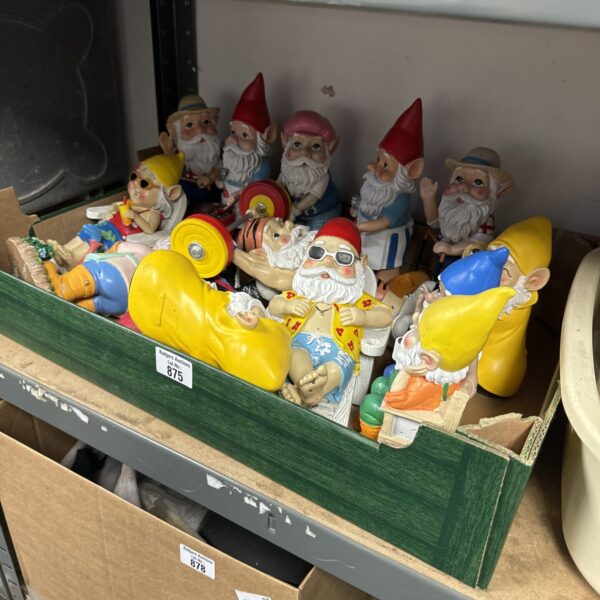 Assorted resin garden gnomes on a tray, colourful garden ornaments.