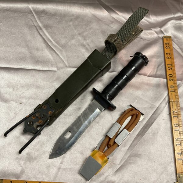 Vintage survival explorer knife with black sheath, showing signs of wear.