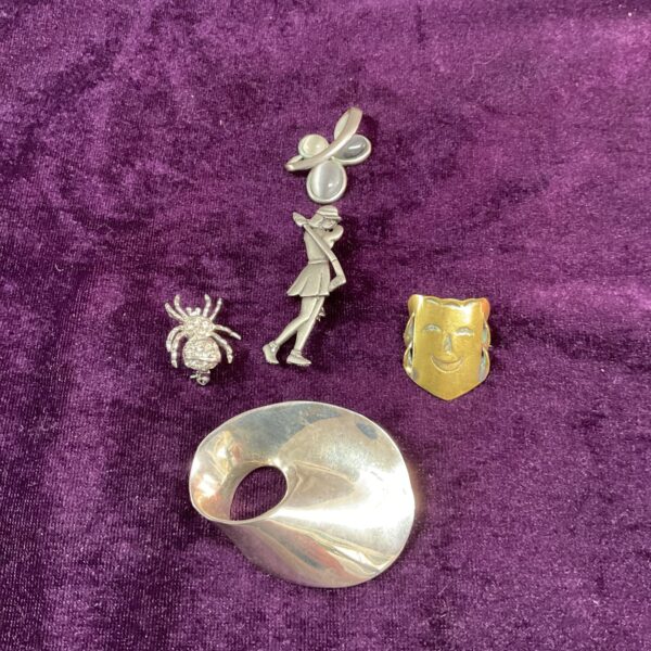 Vintage brooch lot featuring enamel pins and metal jewellery.