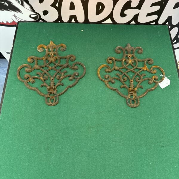 Vintage wrought iron wall plaques with floral designs and hooks.