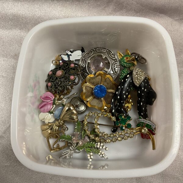 Assorted vintage brooches including enamel pins and floral designs.