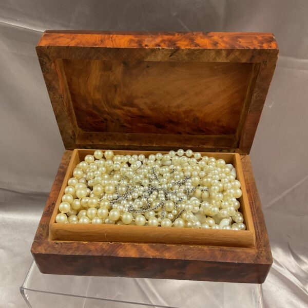 Vintage burr walnut jewellery box filled with pearl necklaces.