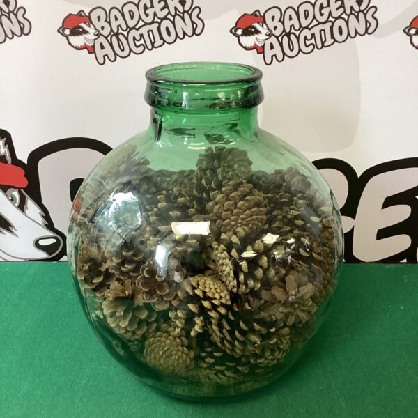 Vintage green glass carboy bottle filled with pine cones.