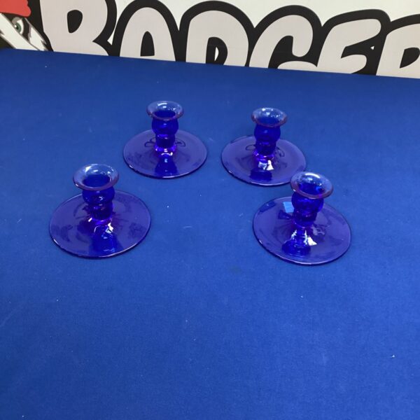 Set of four vintage cobalt blue candle holders on a surface.