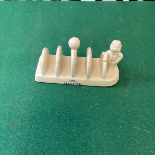 Vintage white enamel Lurpak toast rack for holding bread slices.