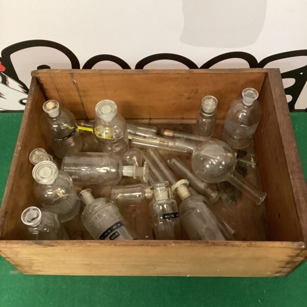 Vintage scientific bottles and test tubes arranged on a wooden tray.