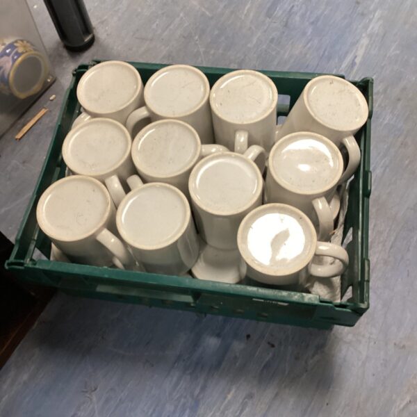 White ceramic mugs in a crate, bulk kitchenware.