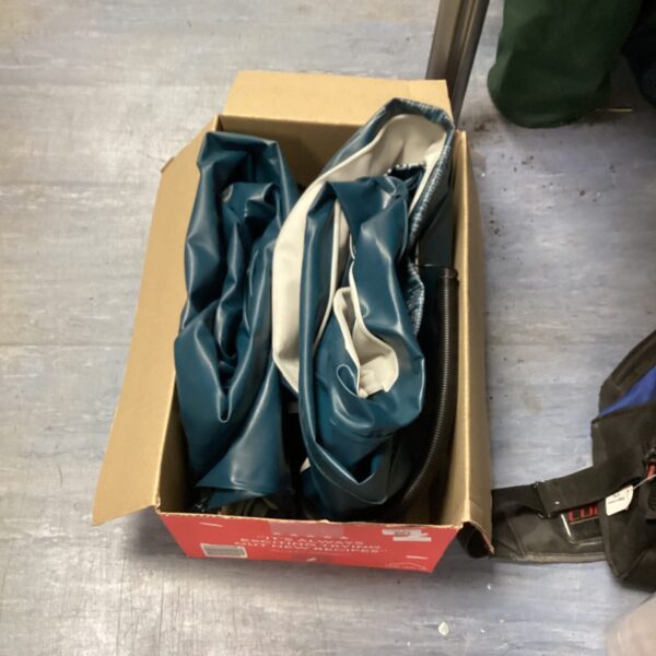 Blue airbed with pump inside cardboard box.