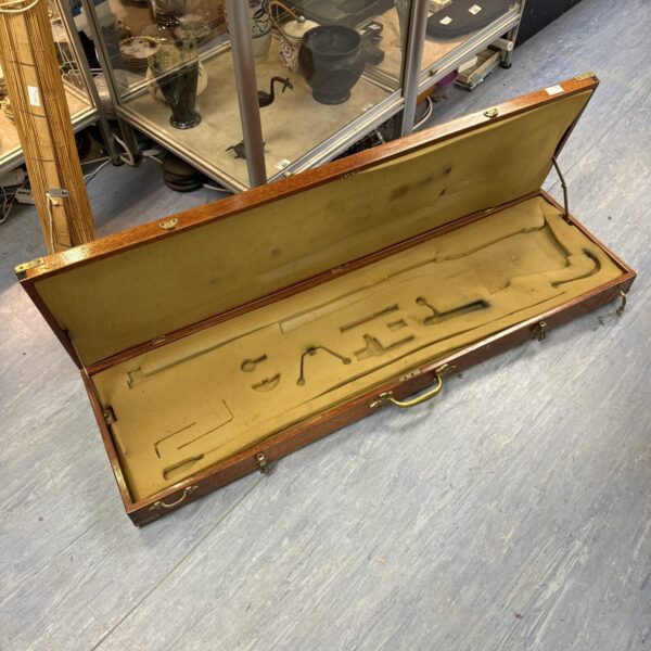 Open vintage rifle case with brass handles, showing green interior.